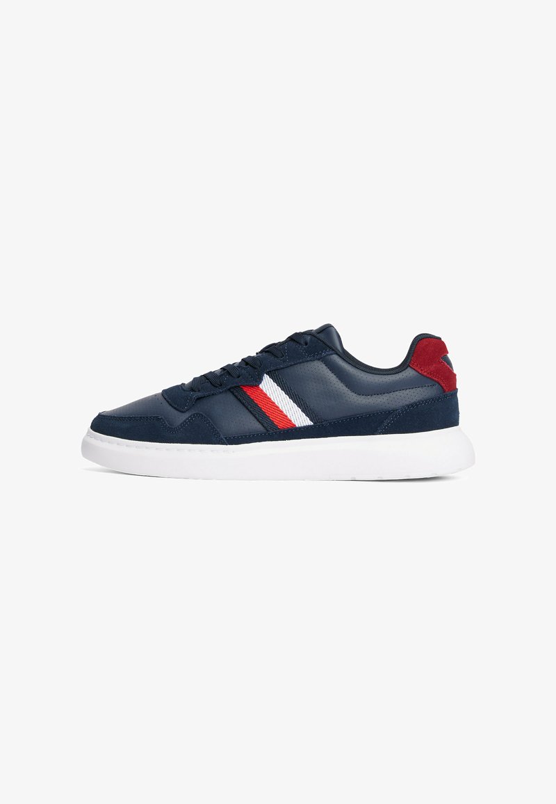 Sneaker navy con tomaia in pelle liscia, suola bianca e accenti a strisce rosse e bianche sui lati. Presenta un tallone in suede texturizzato.