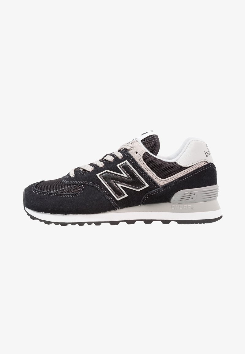 Chaussure de course New Balance noire et grise avec lacets blancs, dessus en mesh et suède, et semelle amortie.