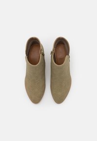 Olivengrønne ankelstøvler lavet af vævet materiale, med spids tå og lynlås lukning på siden. Læder indersål og tan ydersål.