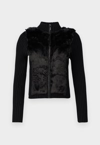 Sort cardigans med lynlås, ribstrikkede ærmer og en blød, tekstureret pelskedel på fronten.