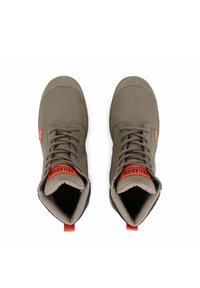 Chaussures montantes en textile vert avec des semelles en caoutchouc noir, présentant des accents et des lacets orange. Comprend une languette en boucle à l'arrière.