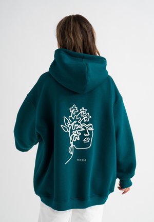Teal oversized hoodie van zacht materiaal, met witte lijntekeningen van een gezicht en bloemen op de achterkant, met ribbels aan de manchetten en de zoom.