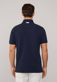 Polo a maniche corte blu navy con colletto e dettaglio azzurro chiaro sul retro. Tessuto liscio e vestibilità regolare.