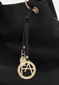 Czarna torebka tote z faux skórki z metalowym pierścieniem w kolorze złotym i zawieszką z logo. Posiada gładką teksturę i zapięcie na sznurek.