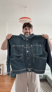 Temno modra jeans jakna z gumbnim zapenjanjem spredaj, dvema žepoma na prsih in kontrastnim šivanjem. Ima klasičen ovratnik in sproščen kroj.