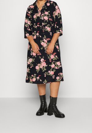 Black midi dress with pink and green floral print, three-quarter sleeves, and black heeled ankle boots with side zippers.