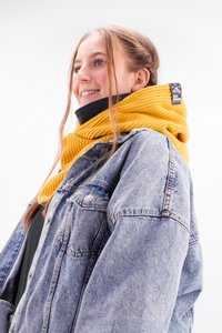 Knitted yellow scarf with a textured pattern wrapped around the neck. Paired with a light blue denim jacket, designed for warmth and comfort.
