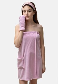 Accappatoio in spugna rosa con una tasca, abbinato a un cerchietto e un guanto coordinati. La texture è morbida e assorbente.