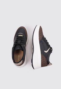 Zapatillas de cuero negro con acentos texturizados en marrón, suela blanca, punta redonda y diseño con cordones. Presentan una marca dorada en la lengüeta.