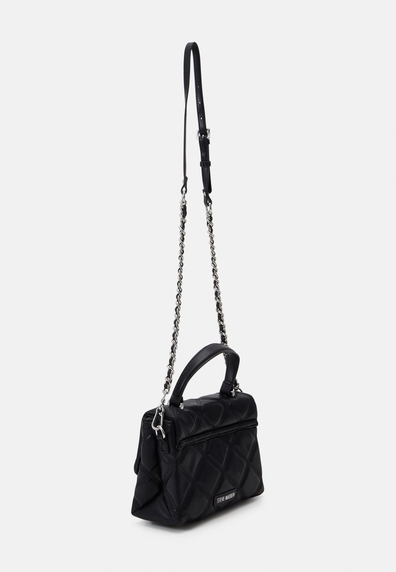 Sac à main noir matelassé avec une poignée supérieure et une longue bandoulière chaîne argentée, présenté sur un fond clair uni.