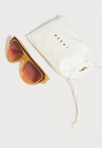 Amber-colored sunglasses with gradient brown lenses next to a white drawstring pouch labeled "MARNI" on a white background.
