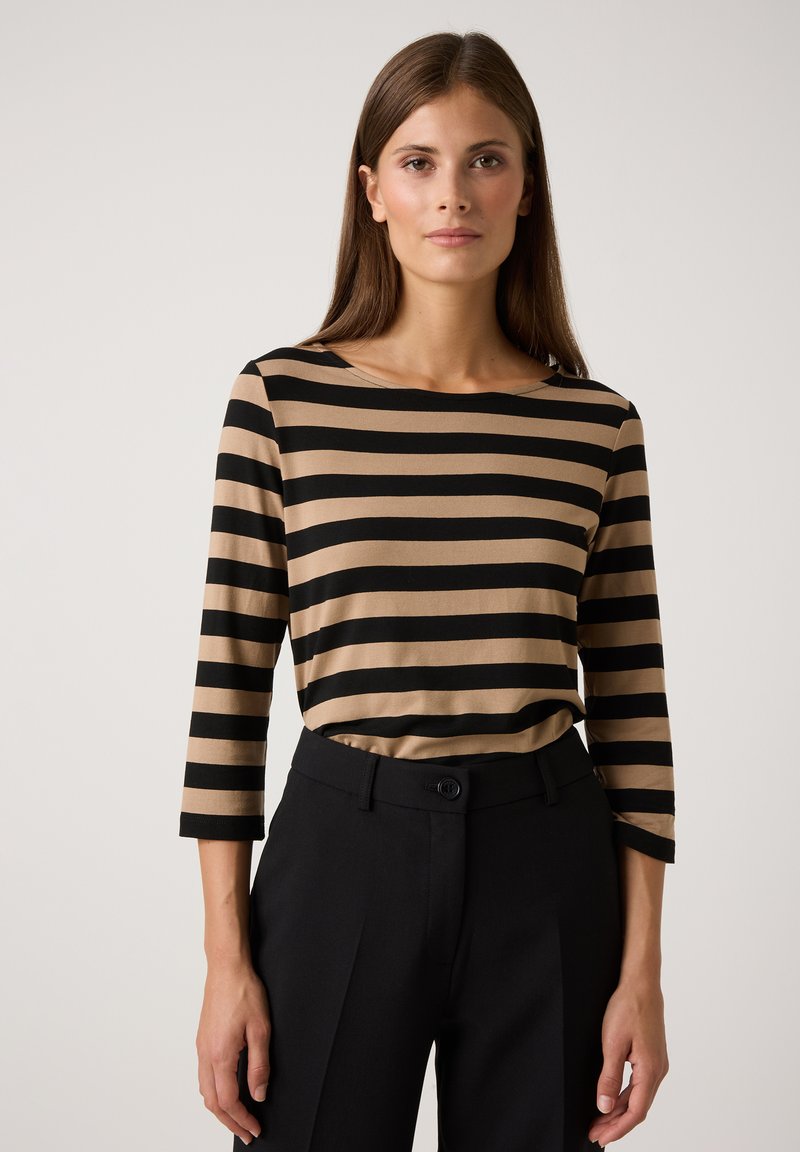 Gestreiftes Langarmoberteil in Beige und Schwarz mit rundem Ausschnitt. Kombiniert mit maßgeschneiderten schwarzen Hosen, die eine glatte Textur aufweisen.