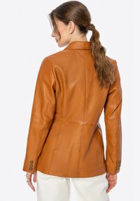 Blazer in pelle marrone con vestibilità sartoriale, design a un solo bottone e bottoni decorativi sui polsini. Texture liscia con silhouette slanciata.