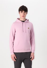 Sweatshirt à capuche rose clair avec une poche à l'avant, arborant un petit logo de papillon jaune sur la poitrine et des poignets côtelés.