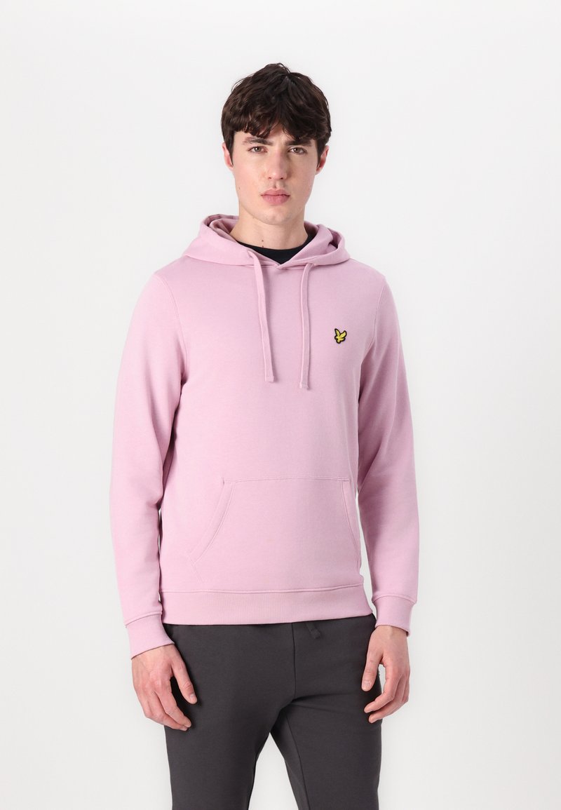 Sweatshirt à capuche rose clair avec une poche à l'avant, arborant un petit logo de papillon jaune sur la poitrine et des poignets côtelés.
