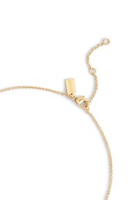 Bracelet en chaîne dorée avec ferret à homard et longueur ajustable, comportant une étiquette rectangulaire portant l'inscription « COACH ». 
