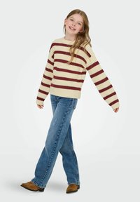 Cream sweater with maroon stripes, crew neckline, and ribbed texture. Paired with blue jeans and brown suede boots.