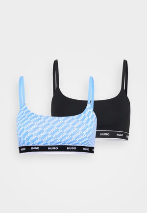 Two bralettes: one in light blue with white repeating "Hugo" logo design, the other in solid black. Both feature adjustable straps and logo bands.