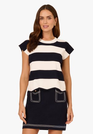 Haut en maille rayé bleu marine et blanc avec des manches courtes et un ourlet festonné, associé à une jupe bleu marine avec des coutures blanches contrastantes et des poches.