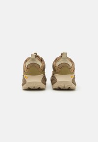 Brown and beige athletic shoes with a textured upper, mesh accents, and a thick, rugged sole featuring a distinctive tread pattern.
