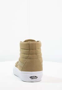 Beige Hohe Vans Sneaker mit weißer Sohle, von hinten betrachtet, zeigt den gepolsterten Schaft und das "Vans Off The Wall"-Logo an der Ferse.