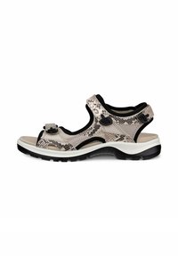 Sandal terbuka berwarna beige dengan pola kulit ular. Memiliki tali yang dapat disesuaikan, alas kaki yang empuk, dan sol bertekstur hitam.