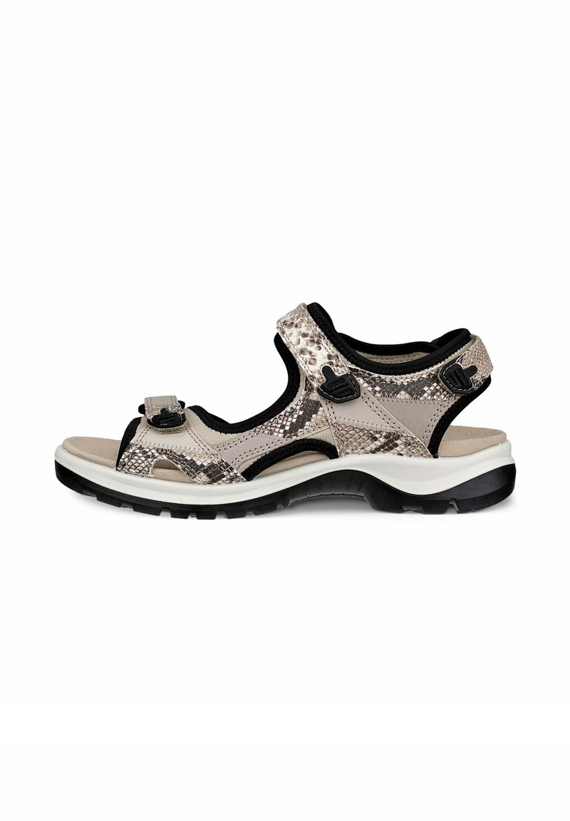 Sandal terbuka berwarna beige dengan pola kulit ular. Memiliki tali yang dapat disesuaikan, alas kaki yang empuk, dan sol bertekstur hitam.