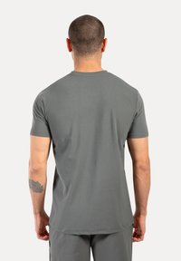 Camiseta atlética gris, de mangas cortas, con cuello redondo, tejido que absorbe la humedad, textura suave, se ajusta cómodamente a la cintura.