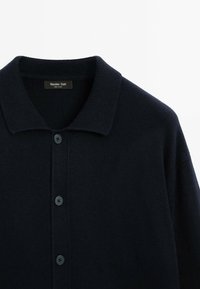 Navy blue knit cardigan with a textured fabric, a flat collar, and front buttons. Label reads "Massimo Dutti," showcasing a classic design.