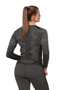 Maglia sportiva a maniche lunghe e leggings neri con motivi testurizzati. Design aderente con pannelli a contrasto e costruzione senza cuciture.