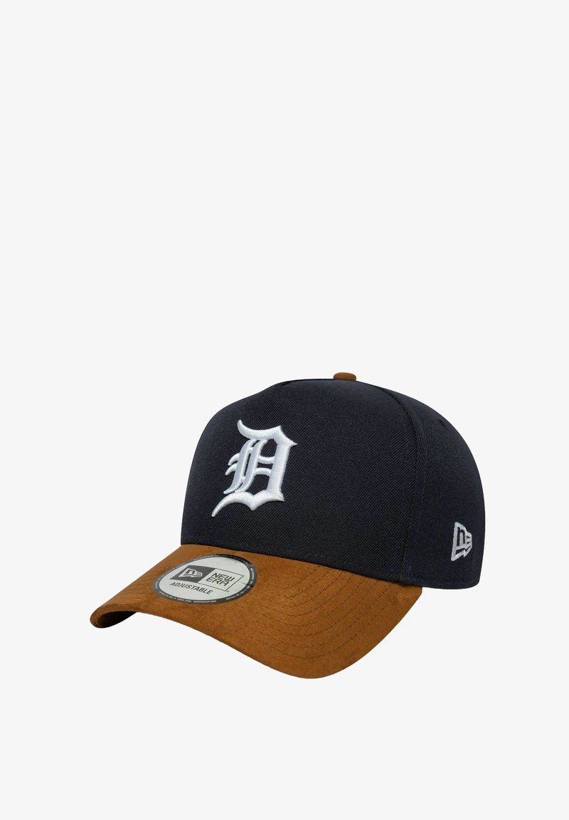 Gorra de béisbol con una corona de tela azul marino y un visera de ante marrón. Decorada con una letra "D" bordada en blanco en la parte frontal.