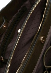 Intérieur d'un sac en cuir vert olive avec plusieurs compartiments zippés, une texture lisse et une doublure à motif dans une teinte plus claire. Accents en métal doré.