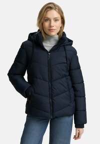 Marineblaue Steppjacke mit Kapuze, Reißverschluss und horizontalem Steppmuster. Weicher Stoff mit elastischen Bündchen und seitlichen Taschen.