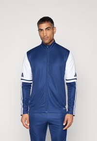 Marineblauw en witte sportjas met een hoge kraag, volledige rits, gladde stof, voorzien van drie strepen op de mouwen en een logo op de borst.