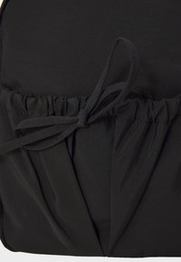 Black fabric bag with gathered detailing at the center, tied at the top with thin fabric strings. Soft texture and matte finish.