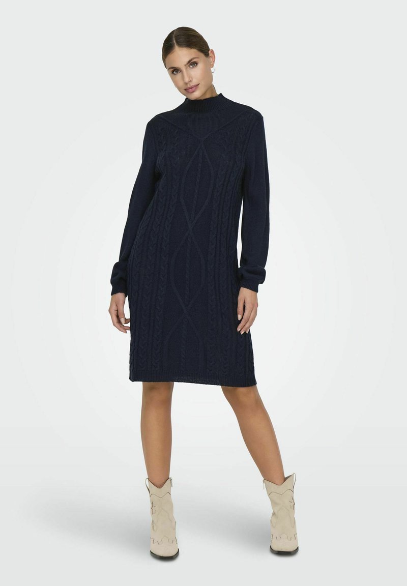 Robe tricotée marine avec un col montant, des manches longues et des motifs en cable texturé. Présente une coupe décontractée, arrivant au-dessus du genou.
