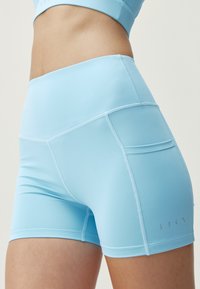 Světle modré sportovní šortky vyrobené z flexibilní tkaniny, s vysokým pasem, prošitými detaily a malou kapsou na boku.