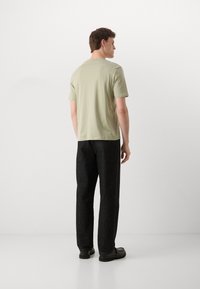 Lys grøn kortærmet t-shirt lavet af bomuld, parret med mørkegrå lige ben bukser. Tekstureret stof med et enkelt design.
