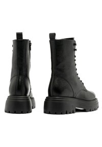 Czarne skórzane botki za kostkę o teksturowanym wykończeniu, z grubą podeszwą, sznurowaniem oraz zamkiem błyskawicznym z boku dla łatwego zakupu.