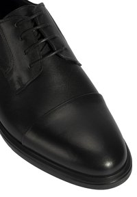 Zwarte leren dress shoe met een soepele bovenkant, cap toe en vetersluiting. Slanke zool met rubberen accenten voor grip.