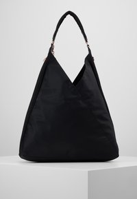 Zwarte nylon tas met een geometrisch driehoekig ontwerp. Voorzien van een enkele handgreep en dubbele ritssluitingen met metalen accenten. Soepele textuur.