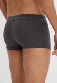 Boxer briefs da uomo grigio scuro realizzati in tessuto morbido, con un cinturino liscio e una vestibilità aderente, progettati per il comfort e la mobilità.