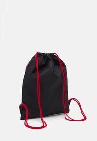Rucsac negru cu șnururi din material, cu șnururi roșii, o textură netedă și un design simplu, funcțional. Fără logo-uri sau modele vizibile.