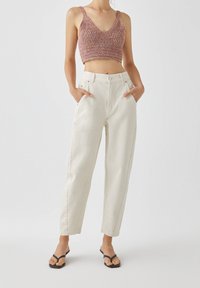 Top de punto corto en hilo multicolor con escote en V; pantalones de tiro alto en color blanco roto con bolsillos; chanclas negras.