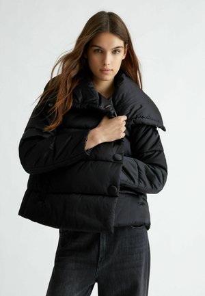 Giubbotto puffer nero con un ampio colletto, dettagli in bottoni e texture trapuntata. Presenta un design cropped e forti caratteristiche di isolamento.
