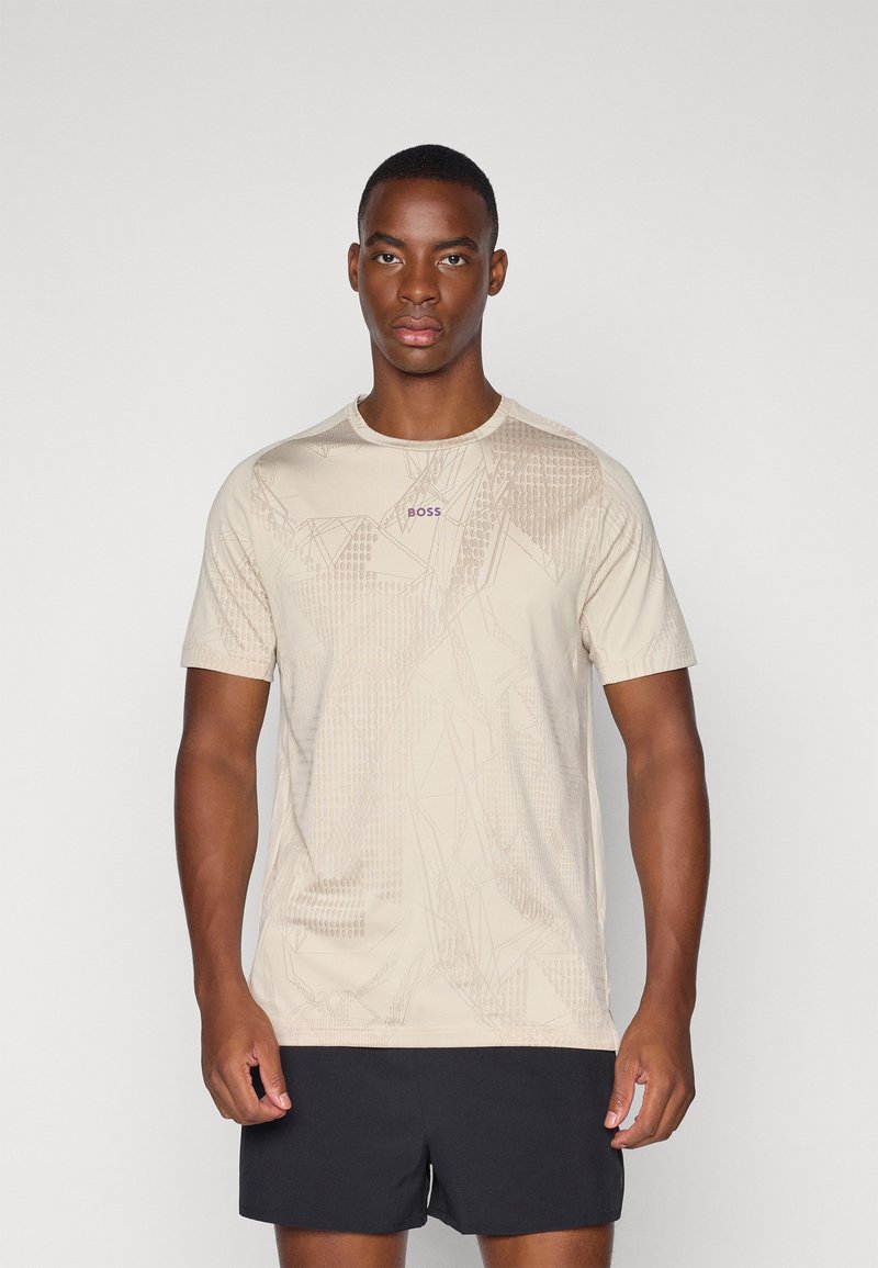 Camiseta de manga corta beige con un patrón geométrico texturizado, cuello redondo y pequeño logo "BOSS" en púrpura en el pecho.