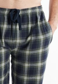 Katoenen geruite pyjamabroek met een marineblauw, groen en wit ruitpatroon, een elastische tailleband met koord en zijzakken.