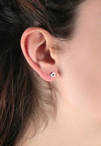 Silberfarbene herzförmige Ohrstecker mit einem kleinen inneren Herzdesign. Sie zeigen eine glatte Oberfläche und ein poliertes Finish.