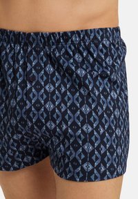 Námorně modré boxerky s geometrickým vzorem ve světle modrých odstínech, elastickým pasem a jedním knoflíkem.