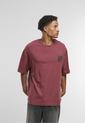 Korte mouwen, loszittend bordeauxrood T-shirt gemaakt van katoen, met een klein zwart rechthoekig logo op de linkerborst.
